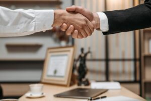 Gros plan d'une poignée de main entre deux professionnels dans un bureau moderne, mettant l'accent sur le partenariat et l'accord.
